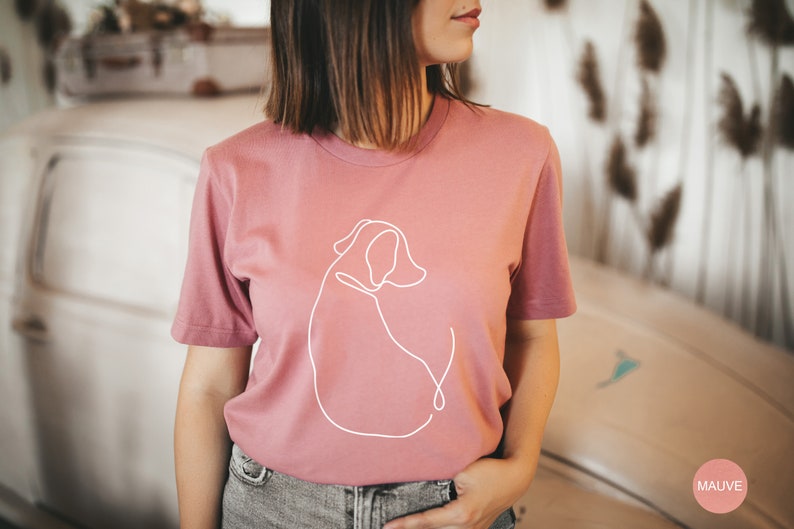 May include: A mauve t-shirt with a white line drawing of a dog on the front. The shirt is made of a soft, comfortable material.