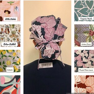May include: A fabric scrub cap featuring a dark navy background with a repeating pattern of large, light pink outlined leaves. The cap has a gathered back section secured with tied fabric straps, showcasing a floral-inspired botanical design.