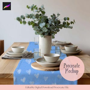 Könnte beinhalten: Ein Holztisch mit einem blauen Tischläufer mit weißen Herzen und kleinen Punkten. Beige Teller, Schalen und Gläser sind arrangiert. Eine weiße Vase enthält Eukalyptus. Der Text "Procreate Mockup" ist sichtbar.