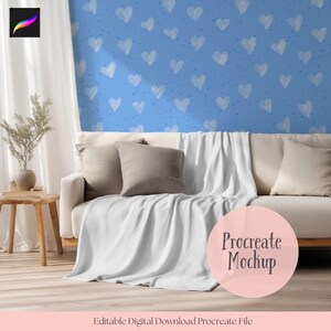 Peut inclure: Scène de salon avec un canapé crème, des coussins et une couverture blanche. Le fond présente un mur bleu orné de motifs de cœurs blancs. Une petite table d'appoint en bois supporte un vase avec des plantes séchées. L'image comprend un graphique Procreate Mockup.