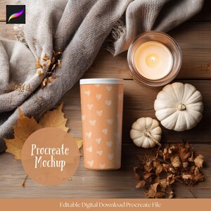 May include: An orange tumbler with white heart patterns, a lit candle in a glass jar, and two white pumpkins are arranged on a wooden surface. A gray scarf and dried leaves add to the autumn theme. The text "Procreate Mockup" is visible.