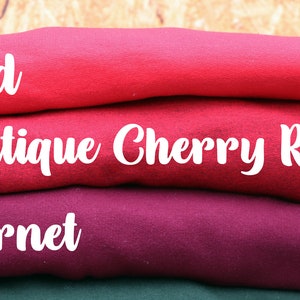 May include: A stack of folded fabric swatches in shades of red, including red, antique cherry red, and garnet.