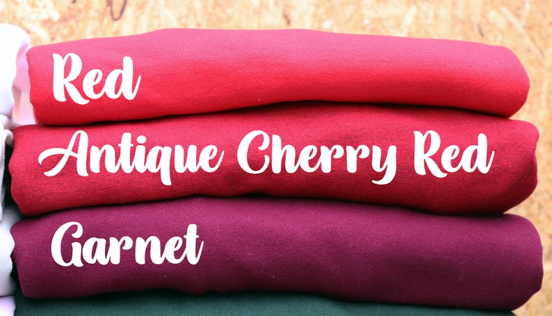 May include: A stack of folded fabric swatches in shades of red, including red, antique cherry red, and garnet.