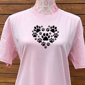 May include: A pink t-shirt with a black paw print design in the shape of a heart.