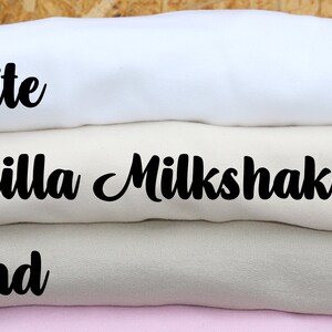 May include: Stack of folded fabric swatches in four colors: white, vanilla milkshake, sand, and pink. The fabric swatches are labeled with the color names.