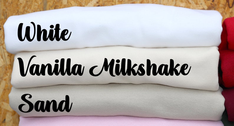 May include: Stack of folded fabric swatches in four colors: white, vanilla milkshake, sand, and pink. The fabric swatches are labeled with the color names.