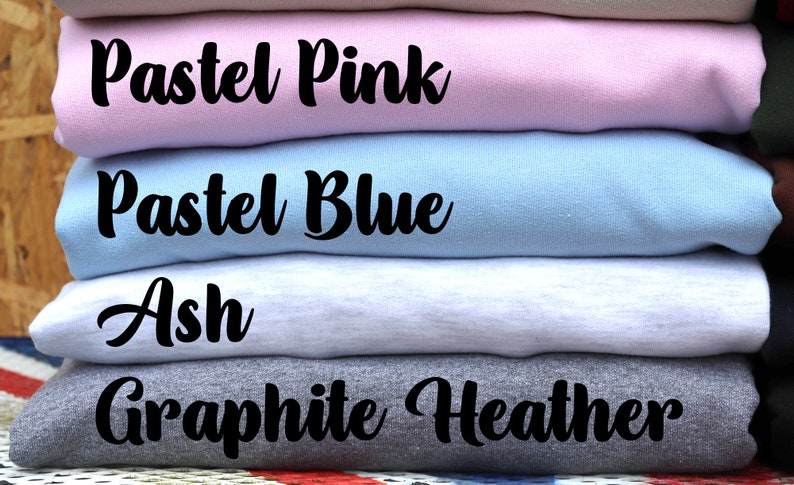 May include: A stack of four folded sweatshirts in different colors. The colors are pastel pink, pastel blue, ash, and graphite heather.