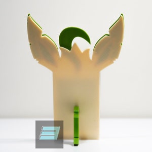 May include: A green and cream-colored decorative figurine with wings and a horn. The figurine is standing on a white surface.
