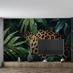 以下が含まれることがあります： 壁に設置された黒いフラットスクリーンテレビ。ジャングルをテーマにした壁紙には、ヒョウ柄が描かれている。壁紙は、ヒョウの毛皮のアップで、緑の葉が描かれている。