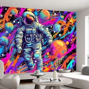 May include: A colorful abstract space-themed wall mural featuring an astronaut in a white spacesuit with a blue helmet floating in a field of colorful paint splatters and planets.