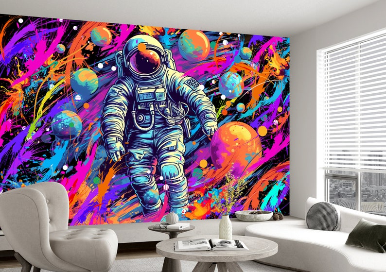 May include: A colorful abstract space-themed wall mural featuring an astronaut in a white spacesuit with a blue helmet floating in a field of colorful paint splatters and planets.