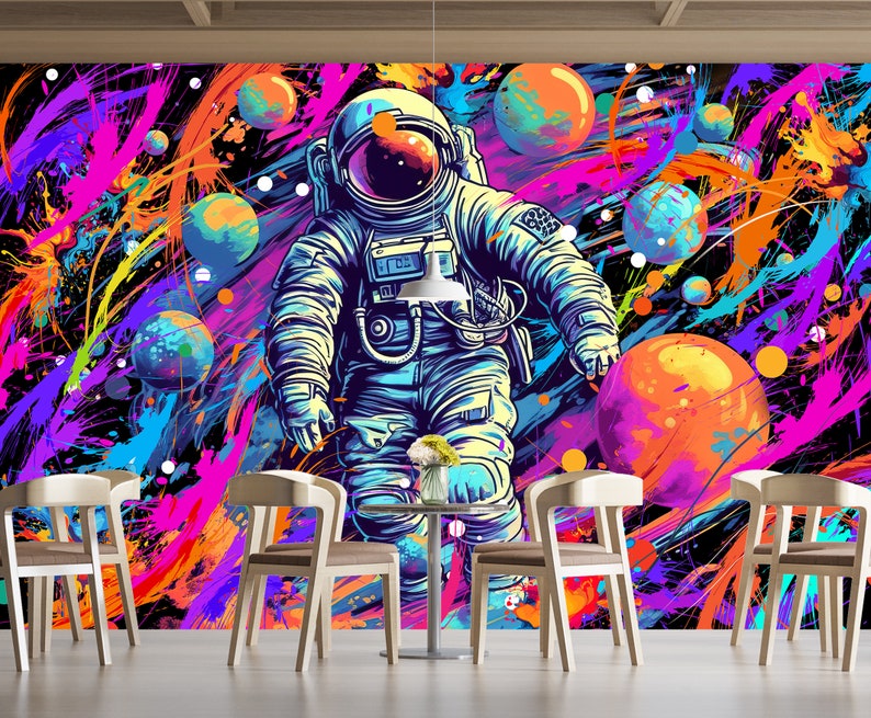 May include: A colorful abstract background with a spaceman in a white spacesuit with a blue helmet. The background is a mix of pink, blue, yellow, and orange paint splatters. There are also several round shapes that look like planets.