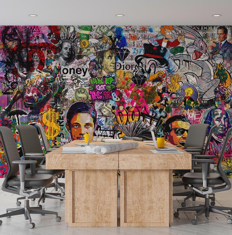 May include: A conference room with a large wooden table and gray office chairs. The wall is covered in a vibrant graffiti mural featuring portraits, cartoon characters, and dollar signs. The mural has a mix of colors.