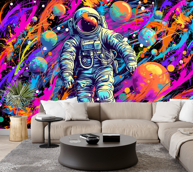May include: A colorful abstract space scene with a blue astronaut floating in front of a large orange planet. The background is filled with splashes of pink, purple, yellow, and blue paint.