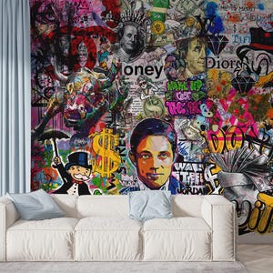 May include: A vibrant graffiti art mural featuring images of money, famous faces, and cartoon characters. The artwork includes a bull, dollar signs, and the word "Money". A white sofa with blue pillows sits in front of the mural.