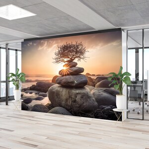 May include: A wall mural featuring a zen garden scene with a stacked pile of stones topped with a small tree, set against a sunset backdrop. The scene is framed by a large window overlooking a city skyline.