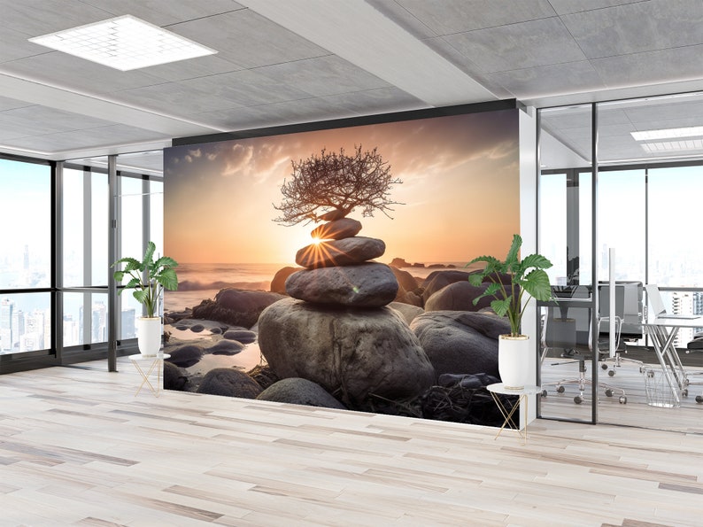 May include: A wall mural featuring a zen garden scene with a stacked pile of stones topped with a small tree, set against a sunset backdrop. The scene is framed by a large window overlooking a city skyline.