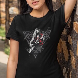 May include: Black t-shirt with a graphic of a musician playing a guitar in front of a Celtic knot design.
