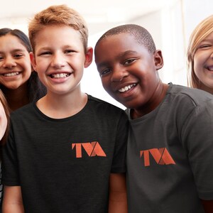 May include: Four children, two wearing black t-shirts with the logo "TVA" in orange, smiling at the camera.