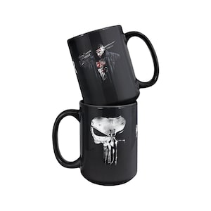 May include: Two black ceramic mugs with a white skull graphic and a graphic of the Punisher character. The mugs are stacked on top of each other.