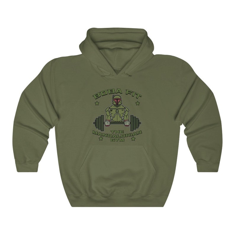 May include: Khaki green hooded sweatshirt with a front graphic. The graphic shows a cartoon Mandalorian character lifting weights, with the text "BOBA FIT THE MANDALORIAN GYM". The sweatshirt has a kangaroo pocket and a drawstring hood.