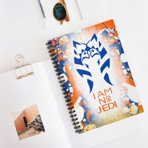Könnte beinhalten: Ein Spiralblock mit einem weißen, blauen und orangefarbenen Sprühfarben-Design. Der Block zeigt eine Silhouette einer Figur aus dem Star Wars-Franchise mit dem Text "I AM NO JEDI".