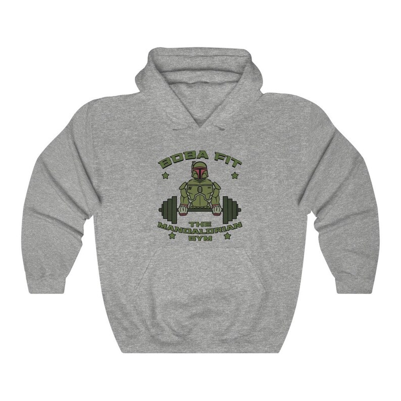 May include: A grey hooded sweatshirt featuring the text "BOBA FIT THE MANDALORIAN GYM" and a green and brown graphic of a character lifting weights. The sweatshirt is made of a soft material and is suitable for casual wear.
