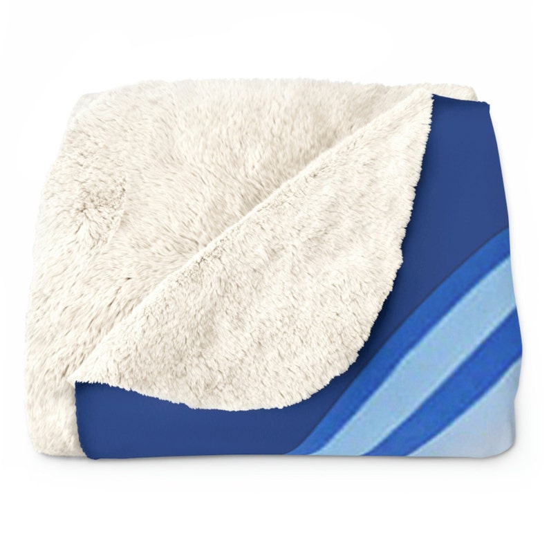 May include: A soft, plush throw blanket with a blue and white striped pattern. The blanket is folded in half, revealing a white sherpa lining.