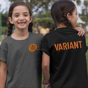 May include: Two children wearing t-shirts. The child on the left is wearing a charcoal gray t-shirt with a small orange logo on the front. The child on the right is wearing a black t-shirt with the word "VARIANT" printed in orange on the back.