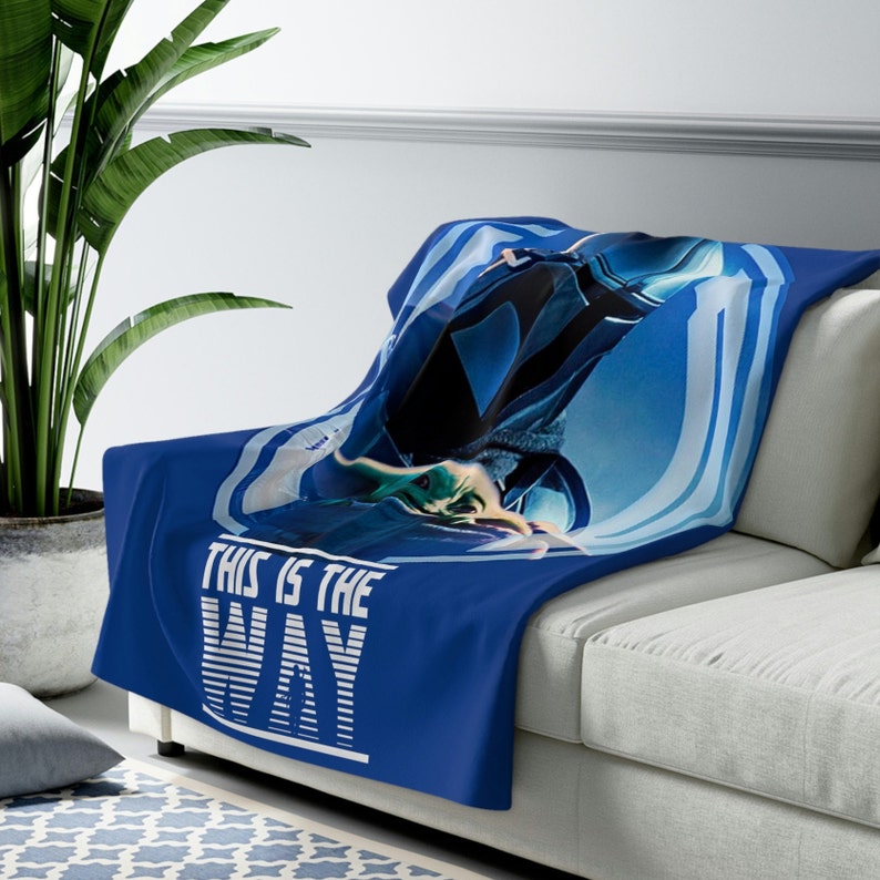 May include: Blue fleece throw blanket with a graphic of a character from the Star Wars series, The Mandalorian, with the text "This is the Way" in white.