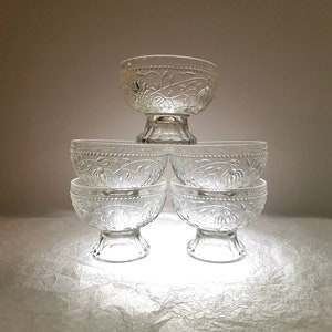 May include: Set of five clear glass bowls with a floral design. The bowls are stacked in a pyramid shape.