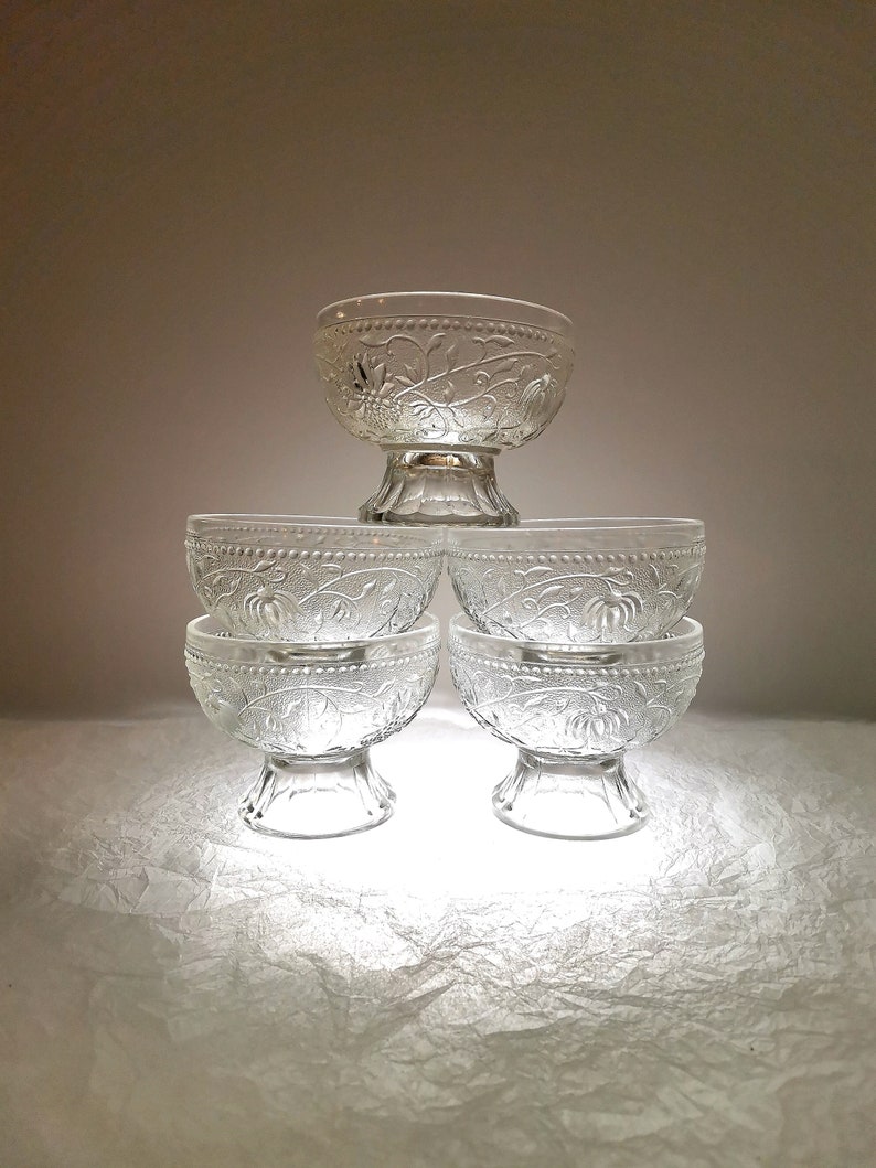 May include: Set of five clear glass bowls with a floral design. The bowls are stacked in a pyramid shape.