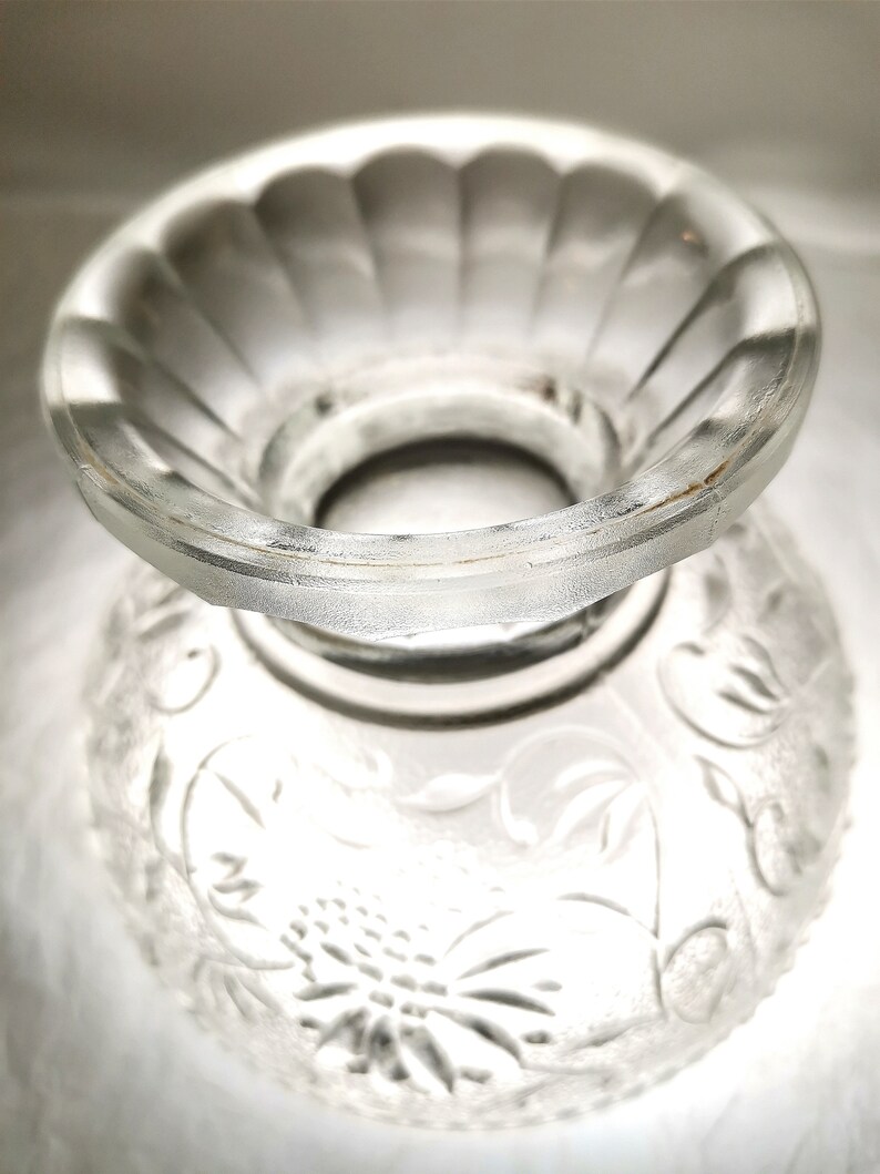 May include: A clear glass bowl with a decorative floral pattern. The bowl has a raised center section with a scalloped edge.