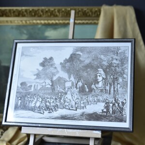 May include: A black and white framed print of a historical scene depicting a crowd of people walking through a wooded area. The print is on an easel and the text at the bottom reads "Wiedner Hauptstrasse, Wien, am 13. November 1848."