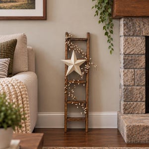 May include: A dark brown wooden decorative ladder leaning against a wall, featuring a large, off-white five-pointed star attached to the center and a delicate vine with small white berries draped across the rungs of the ladder.