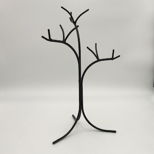 Wrought iron jewelry tree. It looks like an actual tree with no leaves on the branches. The trunk goes down and separates into 3 legs for a sturdy hold. The top breaks into 3 different length branches that each have smaller branches to hang jewelry.