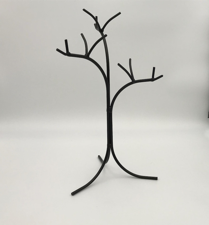 Wrought iron jewelry tree. It looks like an actual tree with no leaves on the branches. The trunk goes down and separates into 3 legs for a sturdy hold. The top breaks into 3 different length branches that each have smaller branches to hang jewelry.