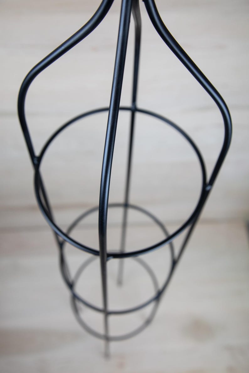May include: Black metal plant stand with three tiers. The stand is designed to support climbing plants.