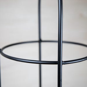 May include: Black metal plant cage with a circular design. The cage is made of sturdy metal and has a simple, modern look.