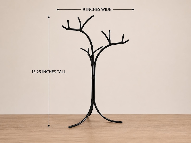 May include: A black metal tree-shaped decorative stand, 15.25 inches tall and 9 inches wide. The stand has a curved base and branches extending upwards. The stand is on a wooden surface.