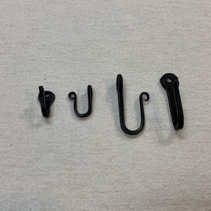 May include: Five black metal hooks of varying sizes, arranged in a row from smallest to largest.