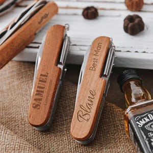 May include: Three wooden pocket knives with personalised engravings. The knives have a silver blade and a brown wooden handle. The engravings read "Samuel Groomman", "Best Man", and "Blake".