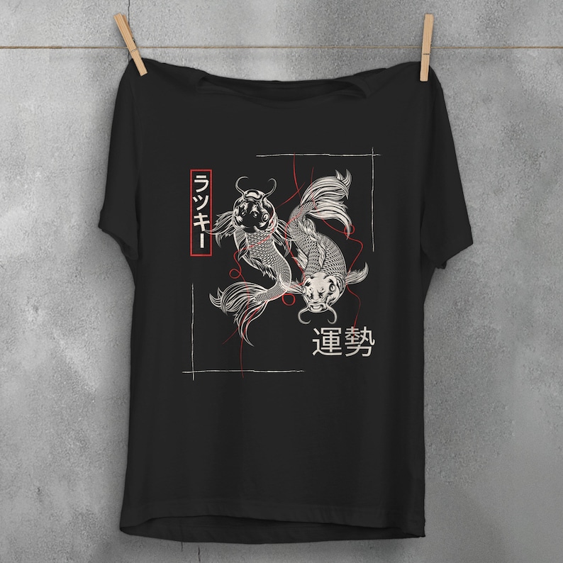 Może przedstawiać: Czarny T-shirt z grafiką przedstawiającą dwa karpie koi pływające w k&oacute;łko. Ryby są białe z czarnymi konturami, a tło jest czarne. Na koszulce nadrukowane są japońskie znaki "ランキ" i "連夢".
