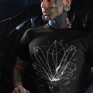 May include: A black t-shirt with a white graphic of geometric crystals. The person wearing the shirt has tattoos on their face and arms.