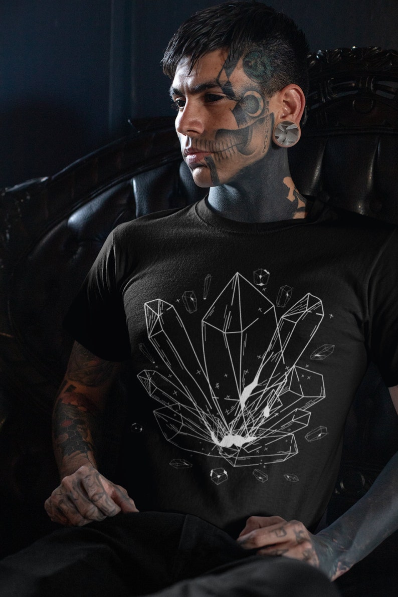 May include: A black t-shirt with a white graphic of geometric crystals. The person wearing the shirt has tattoos on their face and arms.