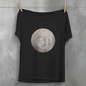 May include: A black t-shirt with a graphic of a full moon and stars on the front.