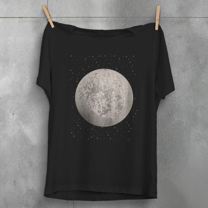 May include: A black t-shirt with a graphic of a full moon and stars on the front.