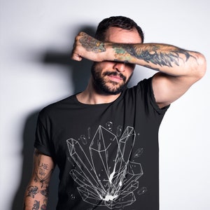 May include: A black t-shirt with a white graphic of geometric crystals. The shirt has a crew neck and short sleeves.