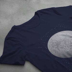 May include: A navy blue t-shirt with a white moon and stars graphic print.