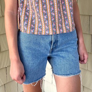 K&ouml;nnte beinhalten: Eine hellblaue Jeans-Shorts mit ausgefranstem Saum. Die Shorts haben einen hohen Bund und eine lockere Passform.